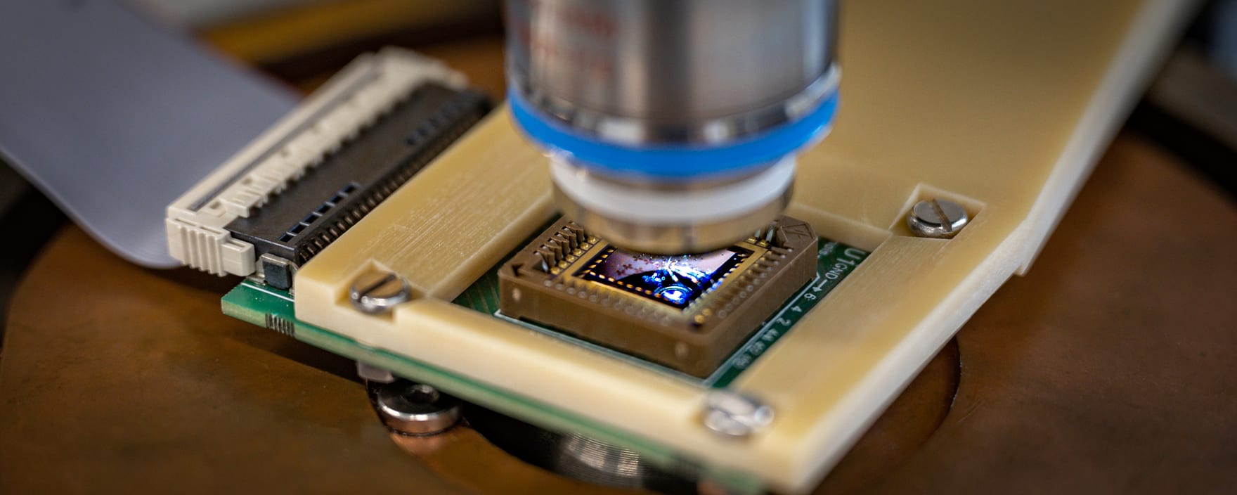A prototype neuromorphic chip under a microscope objective during characterization.